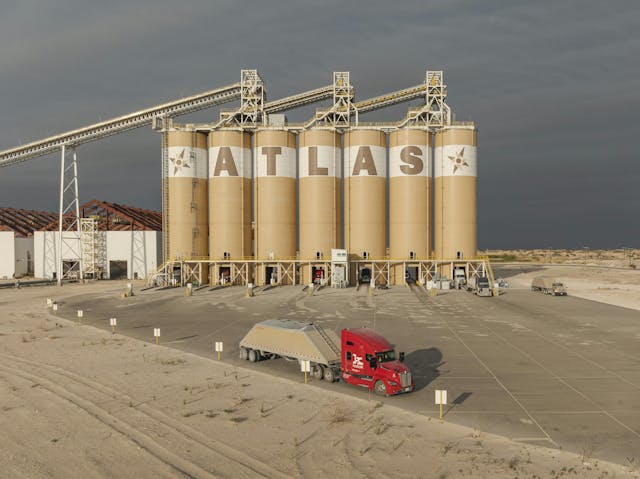 La arena alejada por Atlas Energy Solutions por los camiones Kodiak se utiliza con líquido fracturante durante el fracking hidráulico para mantener abiertas las fracturas en el suelo para la extracción de energía. Proppant sand hauled by Atlas Energy Solutions by Kodiak trucks is used with fracturing fluid during hydraulic fracking to keep ground fractures open for energy extraction.