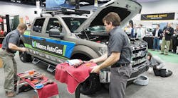 Clock is ticking: Stephen Holland, right foreground, an equipment application engineer at Blossman Services Inc., and Stacey Snyder, a Blossman conversion technician, get started converting the Ford F-150 to LPG.