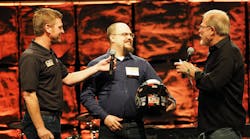 Justin Euler, center, the overall grand champion of this year&apos;s Rush Truck Centers Tech Skills Rodeo, accepts his award onstage with Rush President and CEO Rusty Rush, right, and Clint Bowyer of Stewart-Haas Racing.