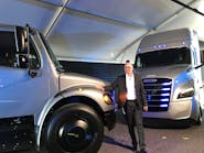 DTNA President and CEO Roger Nielsen poses with the two all-electric Freightliner trucks in June.