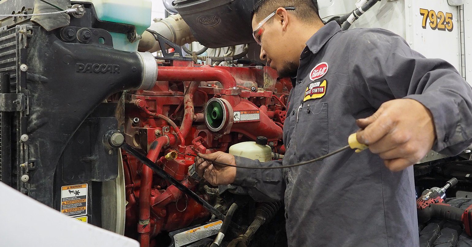 Technician checking truck's engine oil