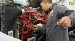 Technician checking truck's engine oil