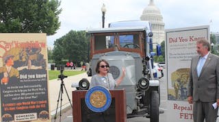 Jodie Teuton, chairwoman of the American Truck Dealers (ATD), explains opposition to the Federal Excise Tax. She stands in front of a Mack truck from the World War I era when FET was implemented.