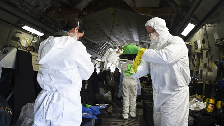 Airmen assist one another in donning their personal protective equipment, while on-board an Air Force C-17 Globemaster III during transportation isolation system training at Joint Base Charleston, South Carolina. Engineered and implemented after the Ebola virus outbreak in 2014, the TIS is an enclosure the Department of Defense can use to safely transport patients with diseases like novel coronavirus.