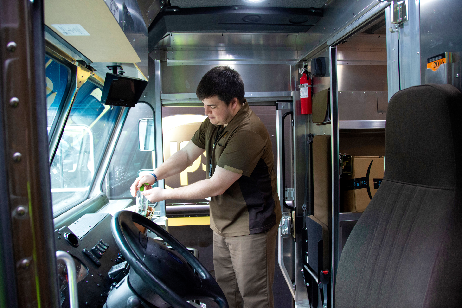 A UPS driver uses hand sanitizer.