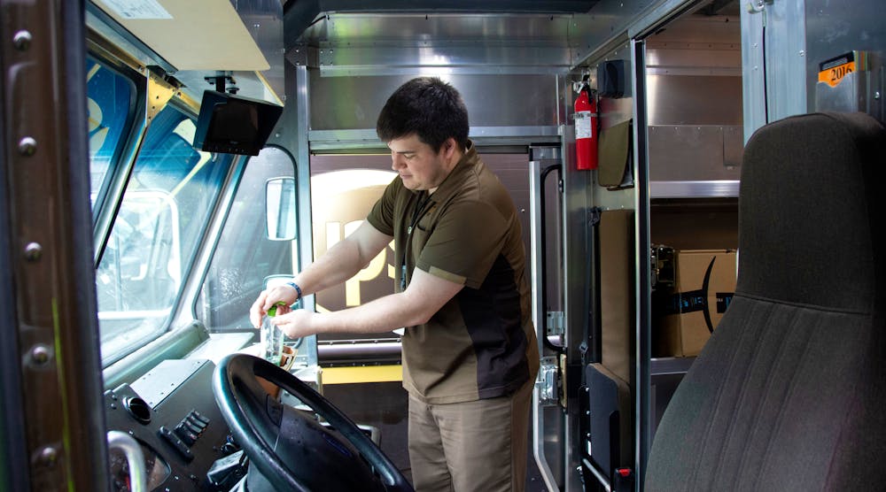 A UPS driver uses hand sanitizer.