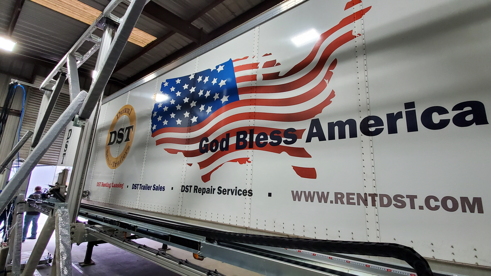 The VAR process involves positioning the vehicle in front of a giant printer that operates on a vertical flatbed frame, where inkjet nozzles traverse on a carriage to robotically paint the vehicle from top to bottom.