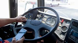 A driver looks at a smartphone while driving.
