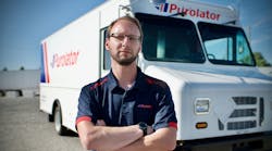 A Purolator driver is shown in front of a Motive EPIC Class 6 step van.