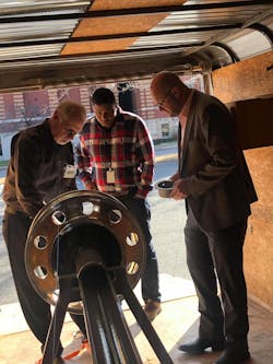 Bill Turner (left) demonstrates how the TetherTech device attaches to the wheel end. The system prevents wheel-off events even in the absence of traditional hub fasteners.