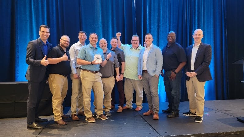The CRH Americas team at NPTC 2023 celebrates their FleetOwner 500 Fleet of the Year award with Jacques DeLarochelliere, co-founder and CEO of ISAAC, left, and FleetOwner executive editor Josh Fisher, right.