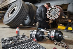 mechanic works with brake in truck repair shop