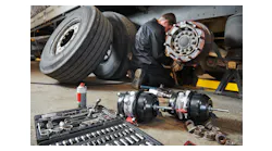 mechanic works with brake in truck repair shop