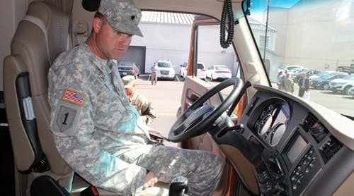 Spec. Charles Bailes gets a feel for sitting in the driver seat of a Kenworth T680 76-inch sleeper during a hiring summit at Joint Base Lewis-McChord (JBLM) in 2015.