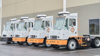 Orange EV electric terminal trucks lined up outside its new headquarters.