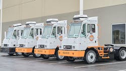Orange EV electric terminal trucks lined up outside its new headquarters. Orange EV electric terminal trucks lined up outside its new headquarters.