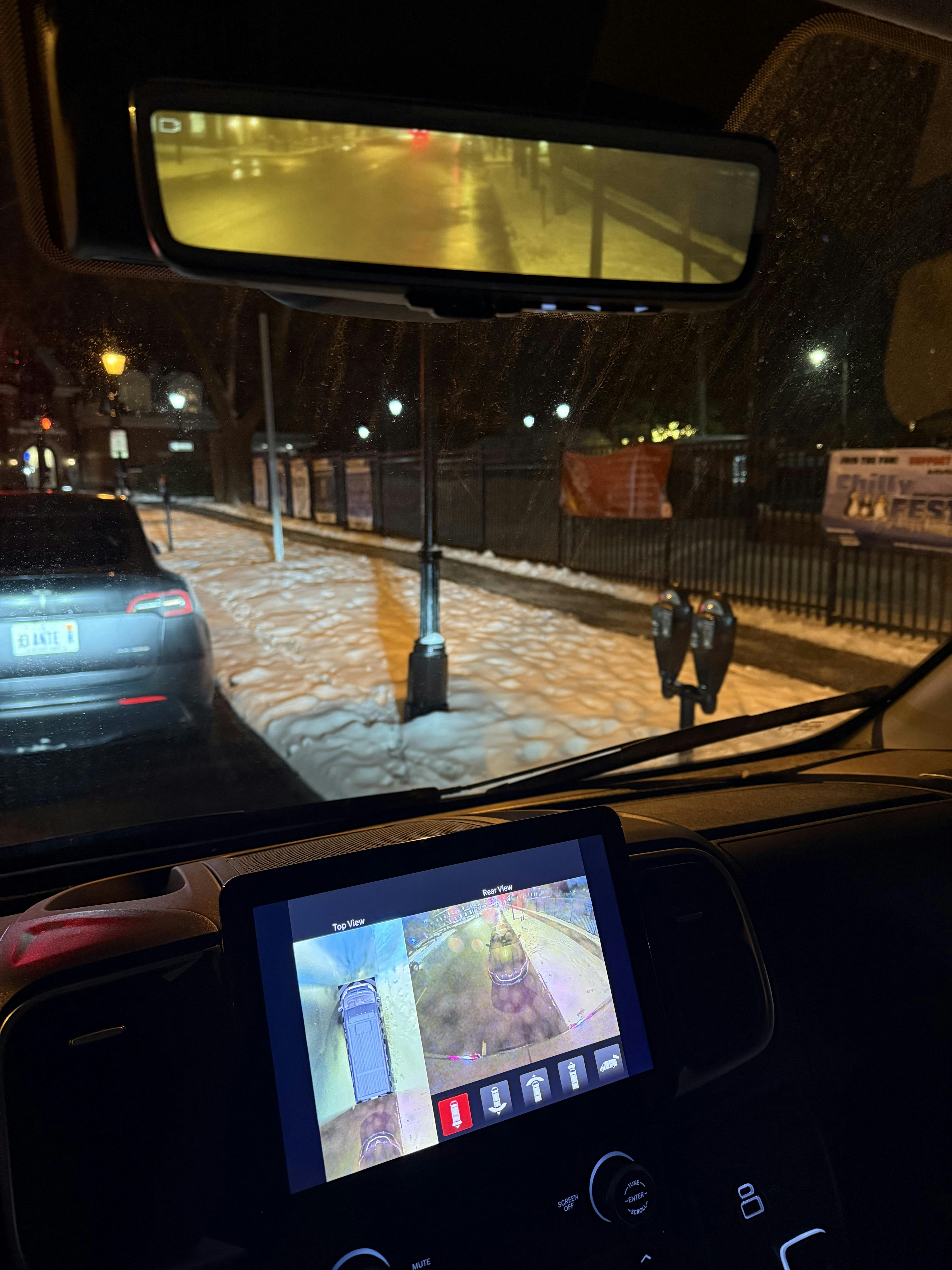 Notice the difference in the view from the rear-view mirror and the back-up camera. The location of the rear-view mirror's camera prevents the driver from seeing the sedan parked directly behind the van.