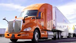 An orange Kenworth Mexicana truck in a parking lot with the sun shining down An orange Kenworth Mexicana truck in a parking lot with the sun shining down