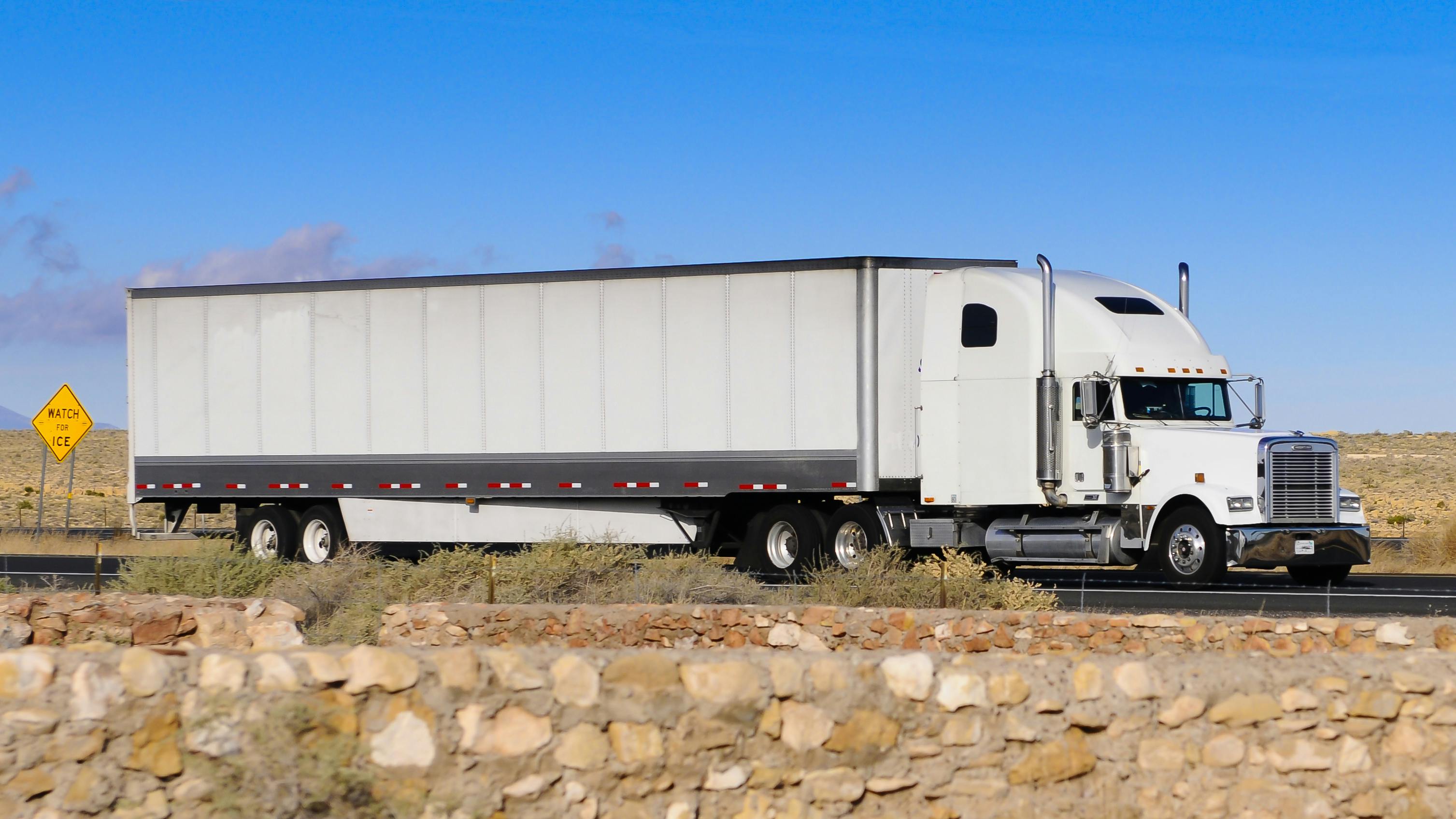 Semi truck traveling over flat, rocky road