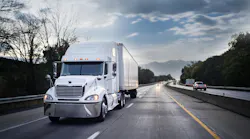 White semi-truck driving on a highway at night, hauling freight with motion blur capturing its speed.