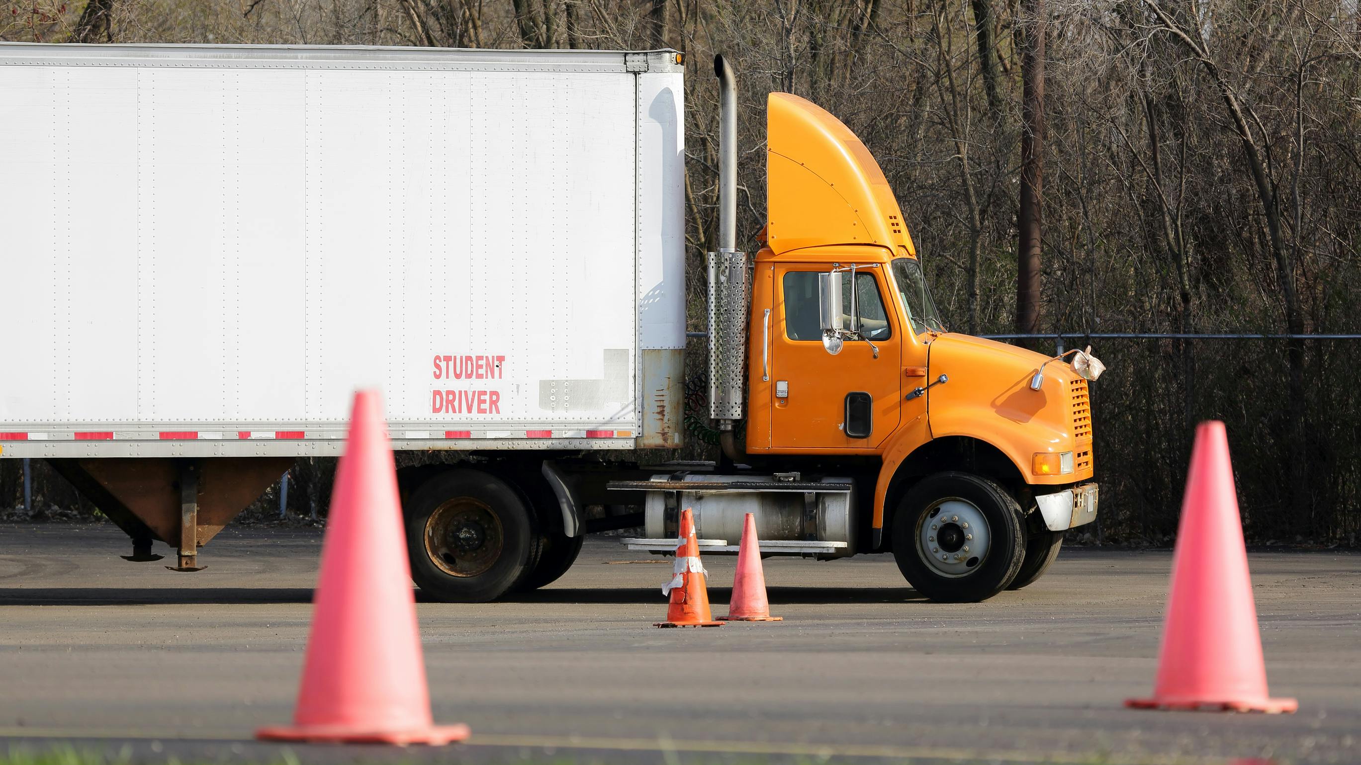 Student truck driver practicing parking maneuvers in a commercial vehicle training yard, focusing on precision and skill development for CDL certification.