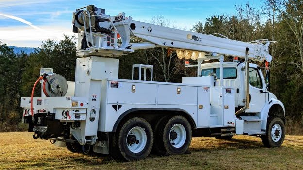 Altec digger derrick truck equipped with hydraulic boom and service body parked outdoors on a job site.