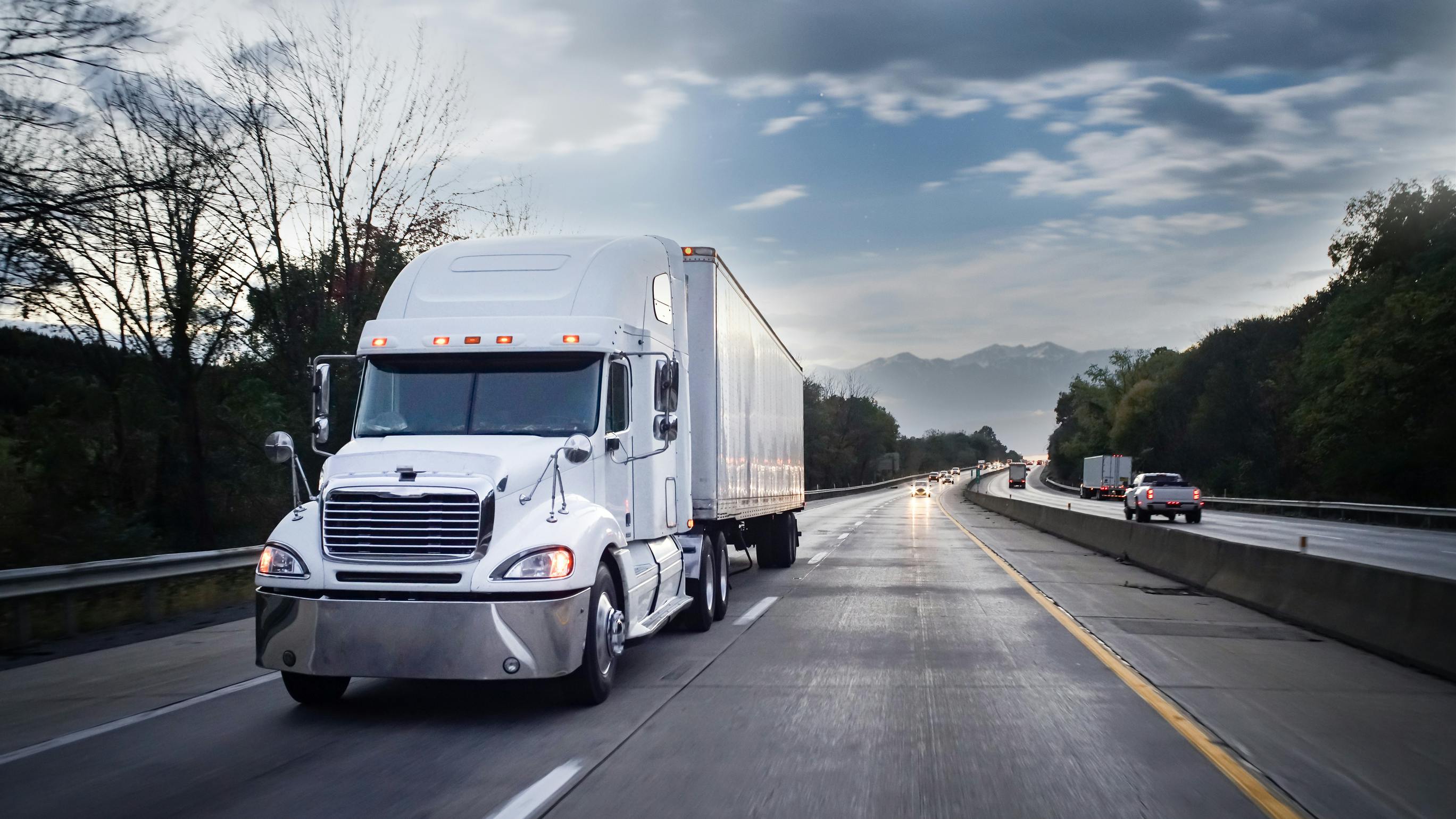 White 18-wheeler semi-truck hauling freight on highway at night with motion blur, illustrating long-haul trucking and nighttime operations.
