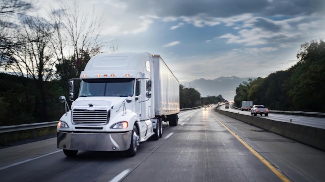 White 18-wheeler semi-truck hauling freight on highway at night with motion blur, illustrating long-haul trucking and nighttime operations.