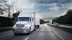 White 18-wheeler semi-truck hauling freight on highway at night with motion blur, illustrating long-haul trucking and nighttime operations.