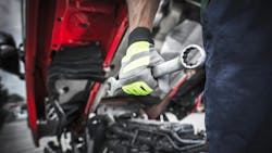 Semi truck technician preparing for work, holding a large stainless steel wrench, performing maintenance and repairs on heavy-duty trucks Semi truck technician preparing for work, holding a large stainless steel wrench, performing maintenance and repairs on heavy-duty trucks