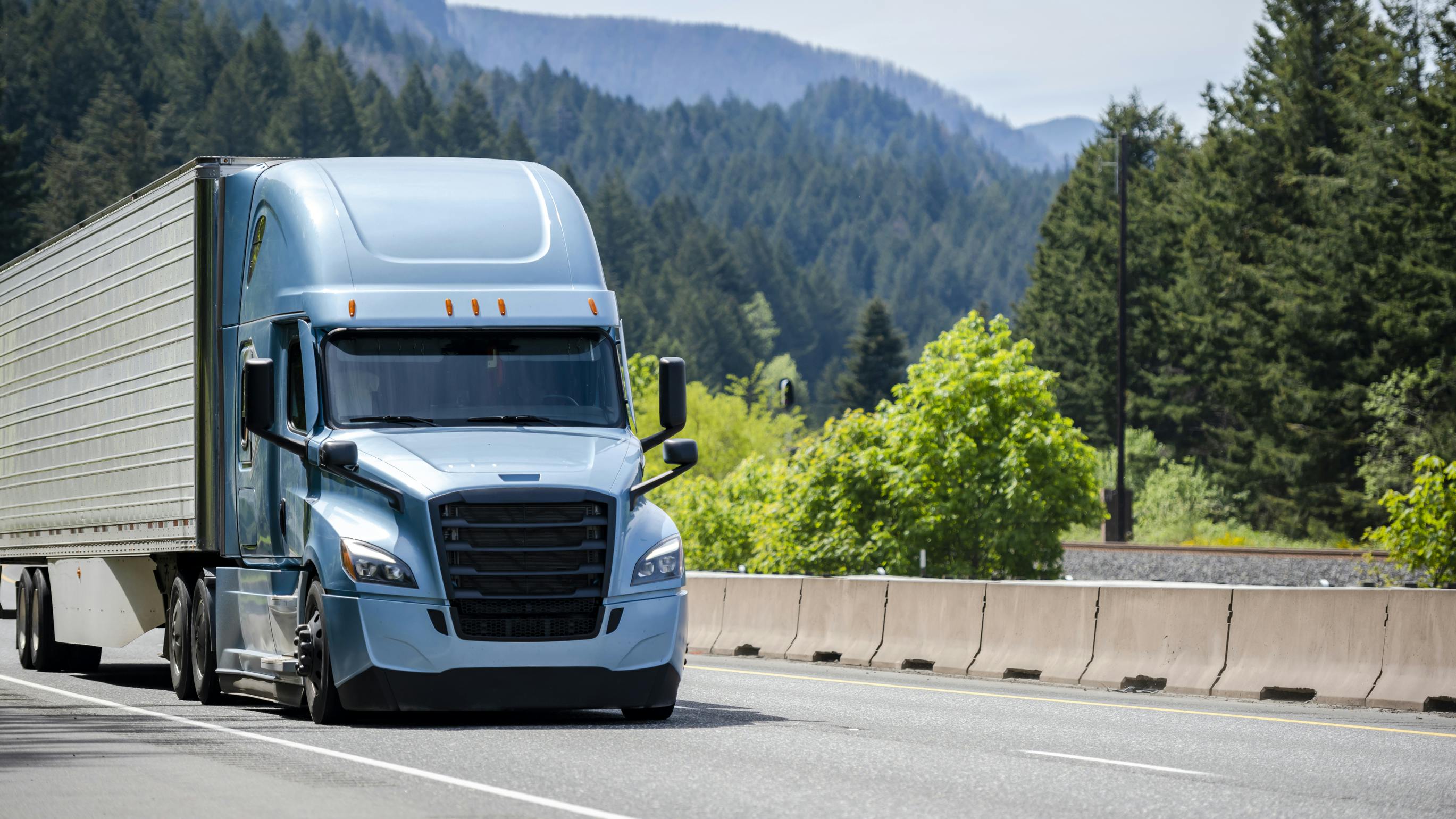 A blue Bonnet semi-truck with a black grille transports cargo in a refrigerated trailer along a highway, illustrating temperature-controlled freight logistics.
