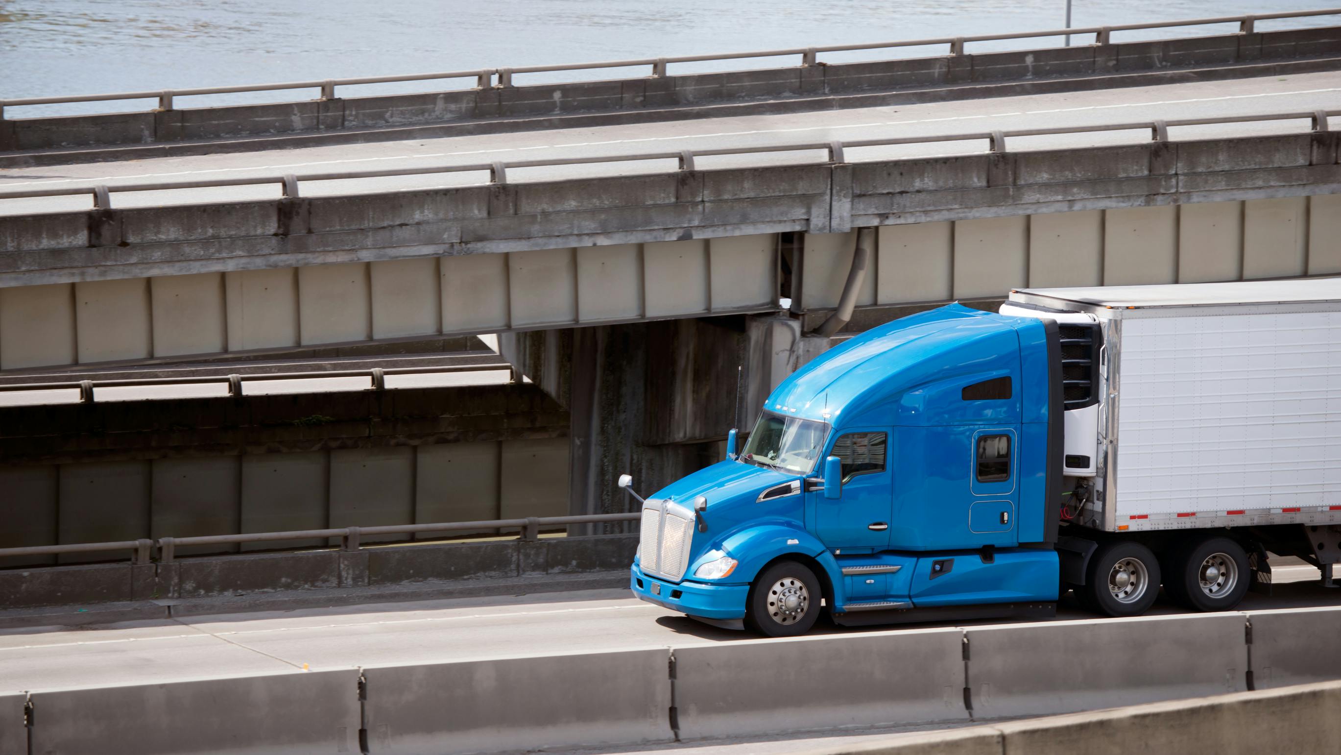 A blue Class 8 semi-truck hauls a reefer trailer on the road, supporting refrigerated transport of perishable food products.