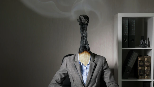 lose-up of a worker with the head of match that is burned out but still smoking, representing modern worker burnout