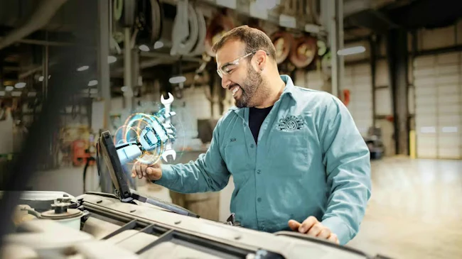 A truck maintenance technician using an advanced diagnostic device to analyze vehicle data in a garage bay, illustrating the application of AI for predictive maintenance and operational efficiency.
