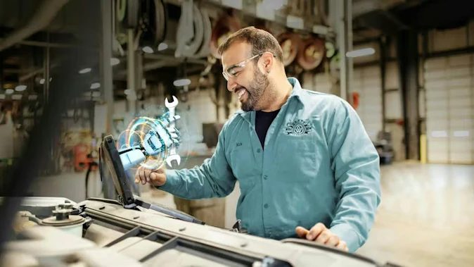 A truck maintenance technician using an advanced diagnostic device to analyze vehicle data in a garage bay, illustrating the application of AI for predictive maintenance and operational efficiency.