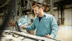 A truck maintenance technician using an advanced diagnostic device to analyze vehicle data in a garage bay, illustrating the application of AI for predictive maintenance and operational efficiency. A truck maintenance technician using an advanced diagnostic device to analyze vehicle data in a garage bay, illustrating the application of AI for predictive maintenance and operational efficiency.