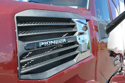 Extreme closeup of the 'PIONEER' chrome nameplate mounted on the dark red hood intake bezel of the new Mack long-haul truck. Extreme closeup of the 'PIONEER' chrome nameplate mounted on the dark red hood intake bezel of the new Mack long-haul truck.