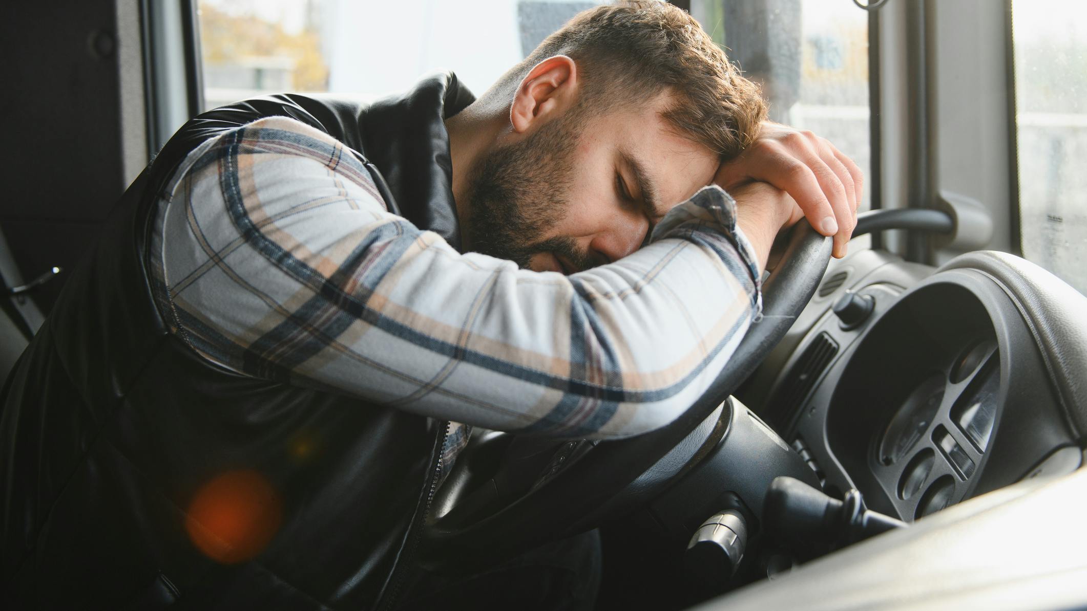 drowsy truck driver resting head on steering wheel