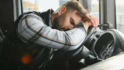 drowsy truck driver resting head on steering wheel