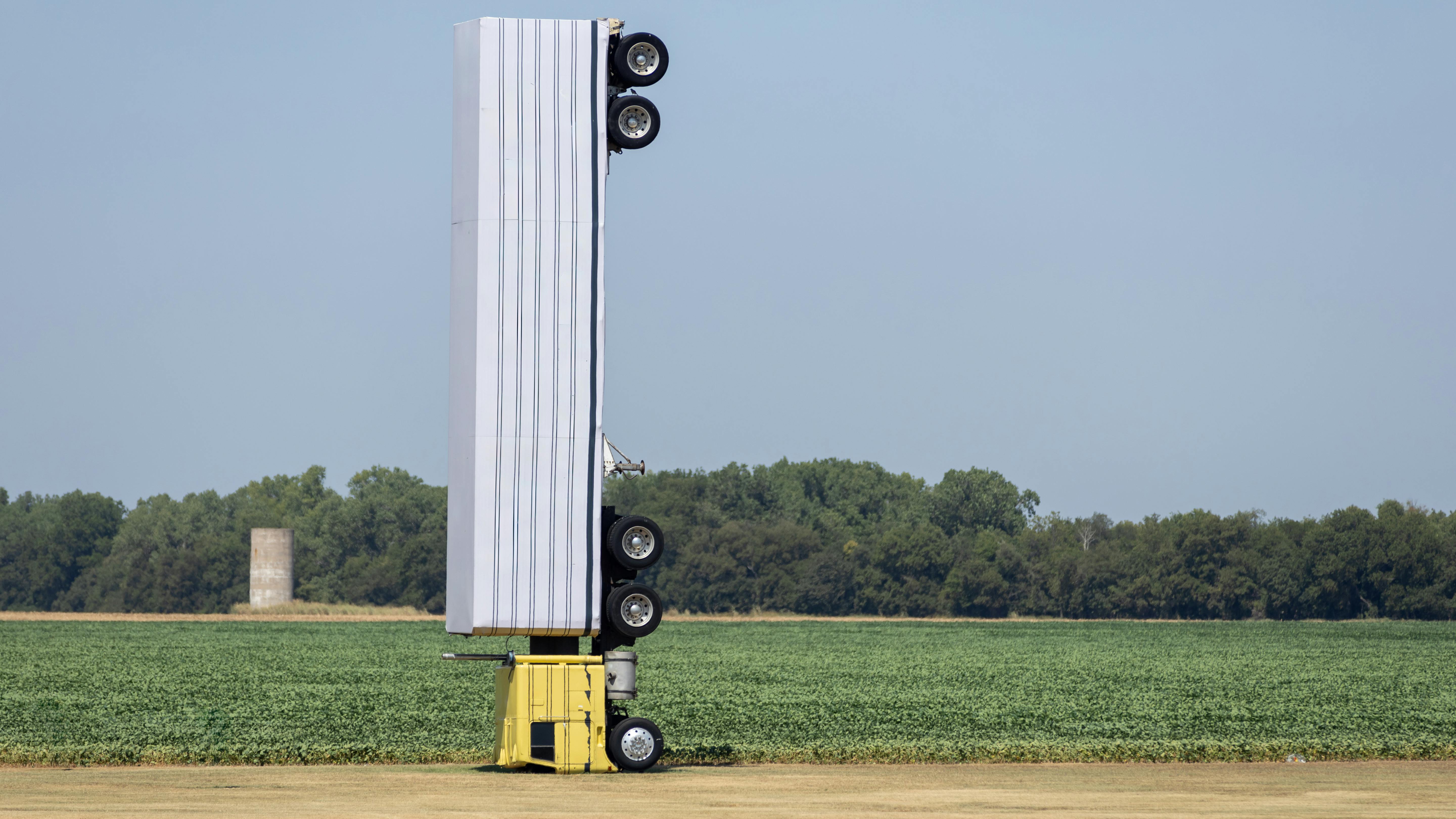 Surreal photo of a commercial semi-truck perched atop a utility pole in an open field, symbolizing a capacity illusio