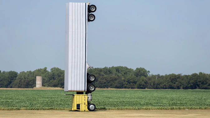 Surreal photo of a commercial semi-truck perched atop a utility pole in an open field, symbolizing a capacity illusio