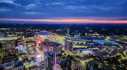 Aerial view of the Atlanta skyline at sunset with Mercedes-Benz Stadium, illuminated city streets, and surrounding buildings.