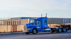 Flatbed semi truck passes a large data center campus under construction