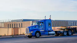 Flatbed semi truck passes a large data center campus under construction