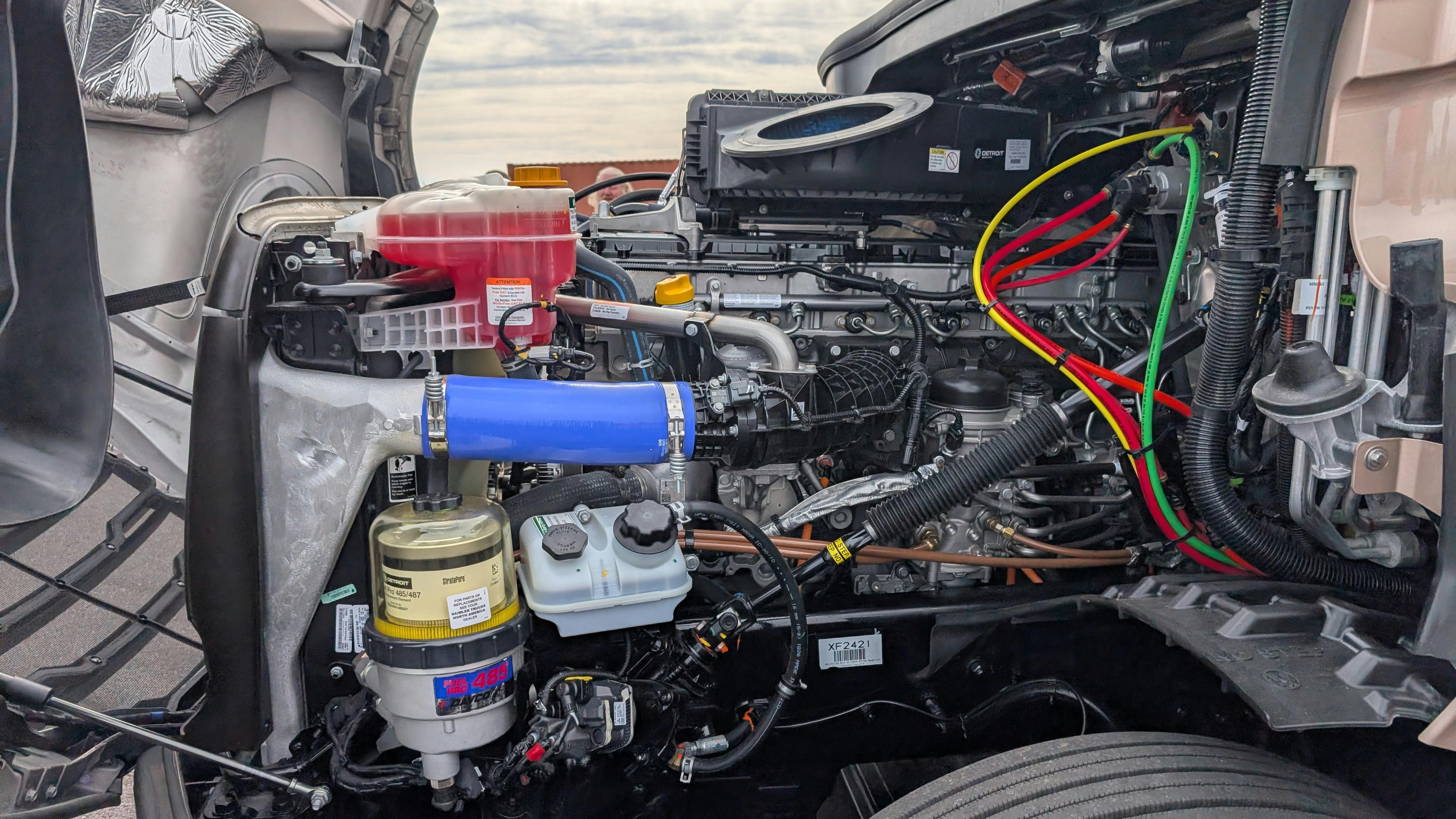The open hood and engine compartment of a Fifth Generation Freightliner Cascadia revealing the heavy-duty Detroit Gen 6 diesel engine.